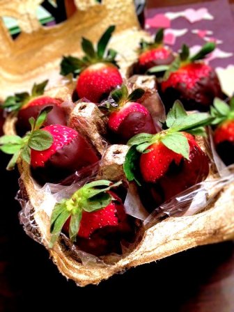 Gold spray painted egg carton lined with saran and holding homemade chocolate covered strawberries.